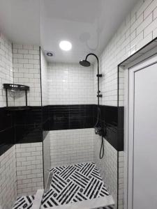 a bathroom with a shower with black and white tile at BlueVibe Apartment in Tbilisi City