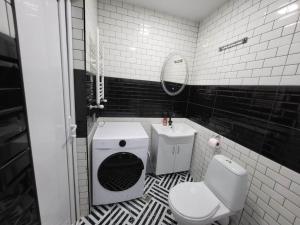 a black and white bathroom with a toilet and a sink at BlueVibe Apartment in Tbilisi City