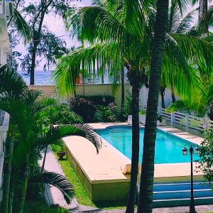une piscine avec des palmiers devant un immeuble dans l'établissement White Sand Cabana, à Flic-en-Flac
