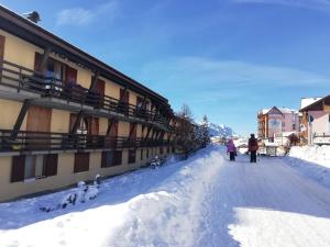 due persone in piedi nella neve accanto a un edificio di DONCIO`S Ski Hike & Bike Apartment a Passo del Tonale