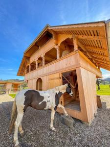 a horse standing in front of a wooden dog house at Ferienhaus Spycher im Emmental in Lützelflüh