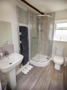 ein Bad mit einer Dusche, einem Waschbecken und einem WC in der Unterkunft Linton Court Coach House in Settle