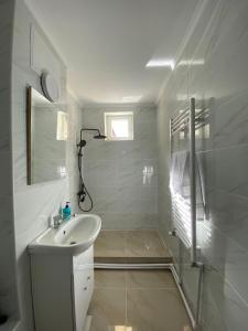 a white bathroom with a sink and a mirror at SorinaApartament in Tîrgu Neamţ