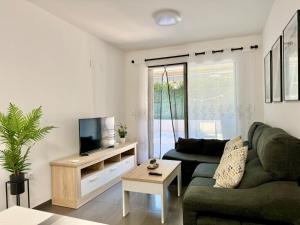 een woonkamer met een bank en een tv bij Apartamento Reformado con Piscina Albir in Albir
