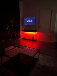 a living room with a tv and a table and a red light at Serenity Residence in The Hague