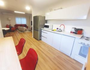 una cocina con armarios blancos y sillas rojas en una habitación en Spacious 3BD Penthouse with Rooftop & Parking en Ra‘ananna