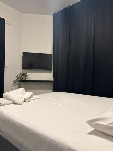 1 dormitorio con 1 cama blanca y TV en Serenity Residence, en La Haya