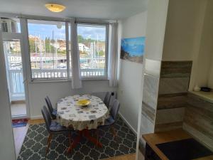 einen Tisch und Stühle in einem Zimmer mit Fenstern in der Unterkunft APARTMENT MARINA VIEW in Zadar