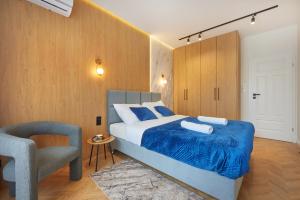 een slaapkamer met een bed met een blauwe deken en een stoel bij Buen Home Apartments - Old Town in Rzeszów