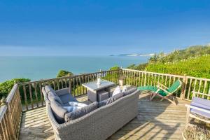 a deck with couches and a table and chairs at Mesmerising sea views - Penrose - above the beach Cornwall. in Downderry