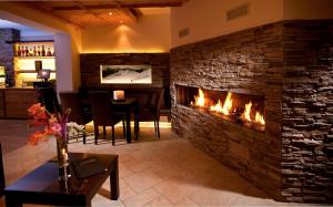 a fireplace in a living room with a dining room at Chasa Castello relax & spa in Samnaun