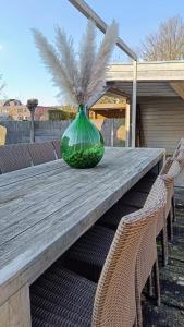 B&B Casa Roman & Vakantiewoning voor 1 pers tot max 30 personen في Zonhoven: مزهرية زجاجية خضراء موضوعة فوق طاولة خشبية