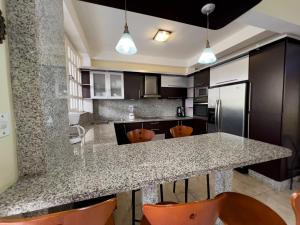 a kitchen with a granite counter top and orange chairs at Tucacasposadas in Tucacas