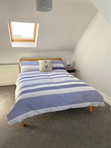 a bedroom with a blue and white striped bed at 2 Headland Place Aberporth (Beautiful sea views, 1 min walk to beach) in Aberporth