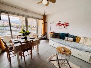 een woonkamer met een bank en een tafel bij Magnifique T2 au calme avec une superbe vue sur le port in Canet-en-Roussillon