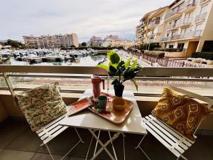 een tafel en stoelen op een balkon met uitzicht op een haven bij Magnifique T2 au calme avec une superbe vue sur le port in Canet-en-Roussillon