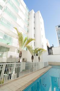 uma piscina em frente a um edifício com palmeiras em Promenade Palladium Leblon no Rio de Janeiro