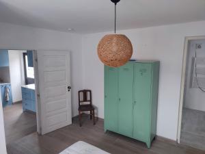 Habitación con armario verde y lámpara colgante. en Vivenda Montanha - Relax in Nature en Alcaria