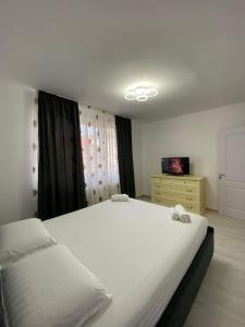 a bedroom with a large white bed and a dresser at SorinaApartament in Tîrgu Neamţ