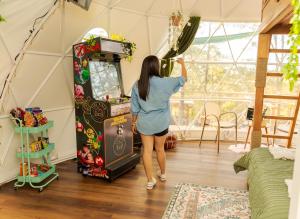 Una donna che gioca a un videogioco in una stanza di Tiny Pines A-Frame Cabin, Domes and Luxury Glamping Site 