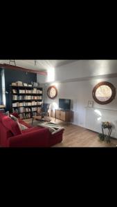 un soggiorno con divano rosso e TV di Péniche logement d'exception sur la Seine Spécial JEUX OLYMPIQUES a LʼÎle-Saint-Denis