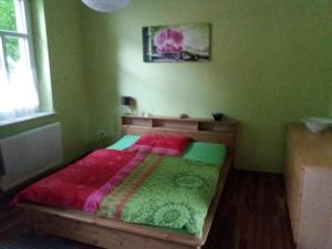 a green bedroom with a bed with a red comforter at Allsaitig Klang- und Seminarzentrum Selb in Selb