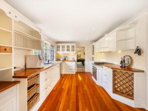 a large kitchen with white cabinets and wooden floors at 4BR German style Villa w Pool Eight Mile Plains in Brisbane