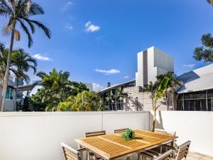 a wooden table and chairs on a patio with palm trees at Central 2BR APT for 6PPL w free parking South BNE in Brisbane