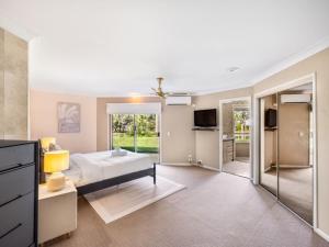 1 dormitorio con 1 cama y puerta corredera de cristal en Modern 4BR Holiday Home W Pool BBQ Oxenford en Gold Coast