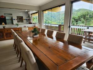 uma sala de jantar com uma grande mesa de madeira e cadeiras em Casa Feliz no Jardim Itaipava, 7 quartos, conforto em Itaipava