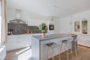 a kitchen with white cabinets and a large island with stools at Huswell - A luminous apartment near the marina in Ostend
