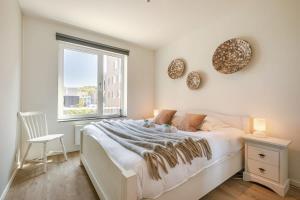 a white bedroom with a bed and a window at Huswell - A luminous apartment near the marina in Ostend
