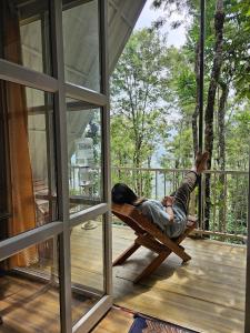 a man is laying in a hammock on a porch at Mount Forest in Meppādi