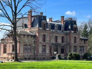 Una gran casa de ladrillo con dos chimeneas encima. en Château de Crènille, en Chaumes-en-Brie