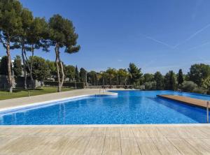 uma grande piscina com água azul e árvores em Duplex vistas mar con piscina em Sant Pere de Ribes