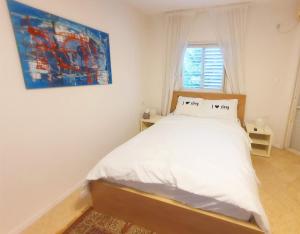 1 dormitorio con 1 cama con una pintura en la pared en Spacious 3BD Penthouse with Rooftop & Parking en Ra‘ananna