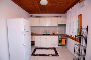a kitchen with white cabinets and a white refrigerator at Casa Chrysi in Mesimvría