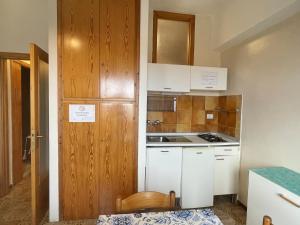 a small kitchen with white cabinets and a wooden door at Cleo Magnolia in Falconara Marittima