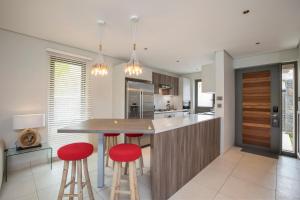 a kitchen with a island with two red bar stools at Modern Villa with Private Pool at Anahita Golf Resort in Beau Champ