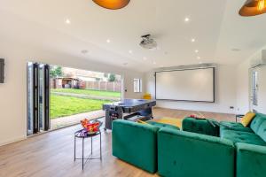 a living room with a green couch and a screen at Robinswood House - A beautiful family home near the Cotswold in Gloucester