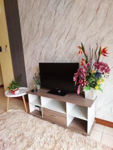una sala de estar con TV en una mesa con flores en KHome-MarinaCourt-KK CITY CENTRE .3B2R(8Pax) NEW!! en Kota Kinabalu
