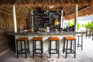 a bar with four bar stools in front of a restaurant at What The Duck Backpackers in Canggu