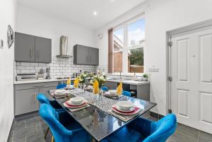 a kitchen with a table and blue chairs at Spacious and Stylish House - Sleeps 12 in Sheffield