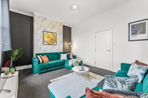 a living room with a green couch and a table at Spacious and Stylish House - Sleeps 12 in Sheffield