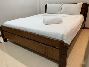 a bed with a wooden frame with a white pillow on it at Bonsai Villa @ Mesilou 盆栽小苑 in Kampong Kundassan