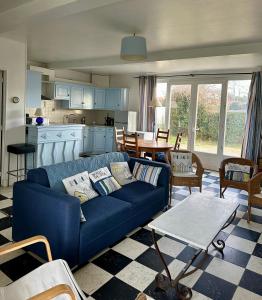 a living room with a blue couch and a kitchen at VILLA LES MOUETTES - Maison 8 couchages in Quiberville