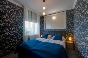 a bedroom with a bed with blue sheets and floral wallpaper at APARTAMENTY in Przemyśl