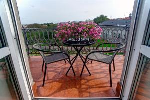 stół z różowymi kwiatami na balkonie w obiekcie APARTAMENTY w mieście Przemyśl