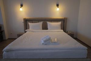 Una cama con dos toallas y un libro. en Hotel Denis en Pristina