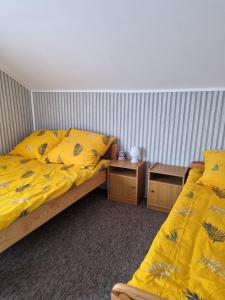 two beds in a room with yellow sheets and tables at Nad jeziorem u Beaty in Jezierzany